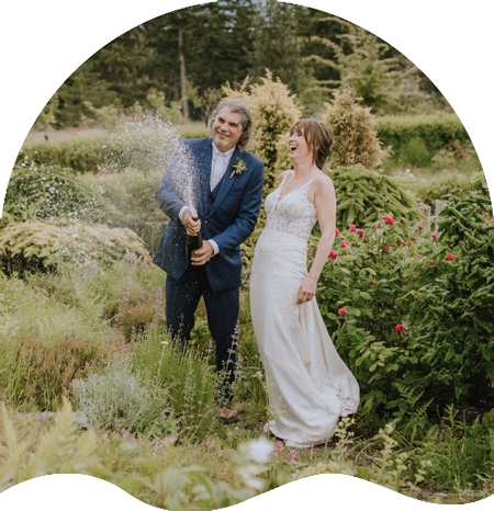 Orcas Island Weddings Entertainment bride and groom popping champaigne in a garden and laughing